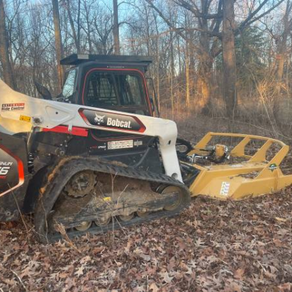 A bobcat tractor is sitting in the middle of a forest
