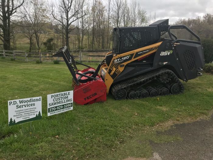 A snow blower is parked in a grassy field next to a sign.