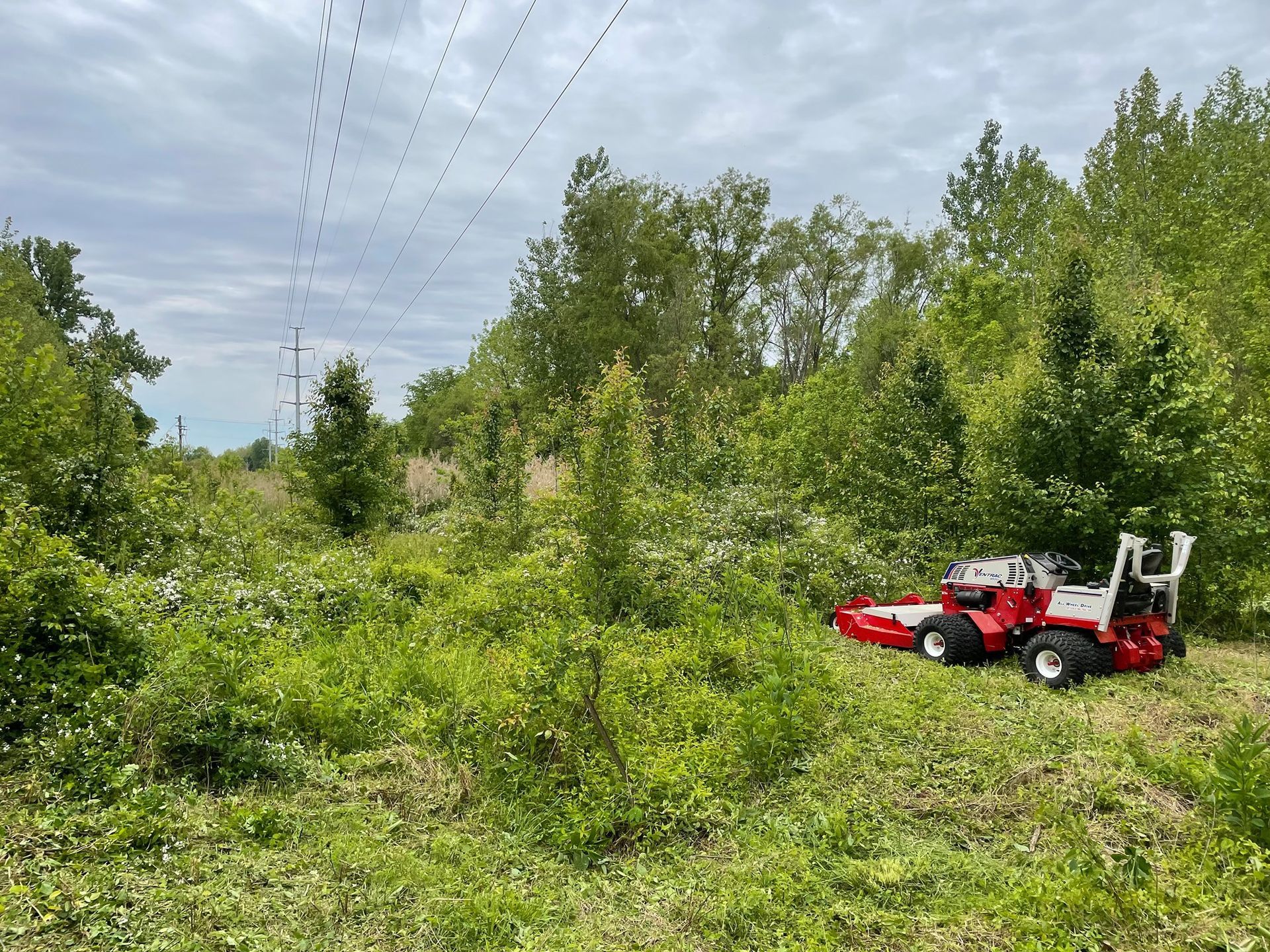 A snow blower is parked in a grassy field next to a sign.