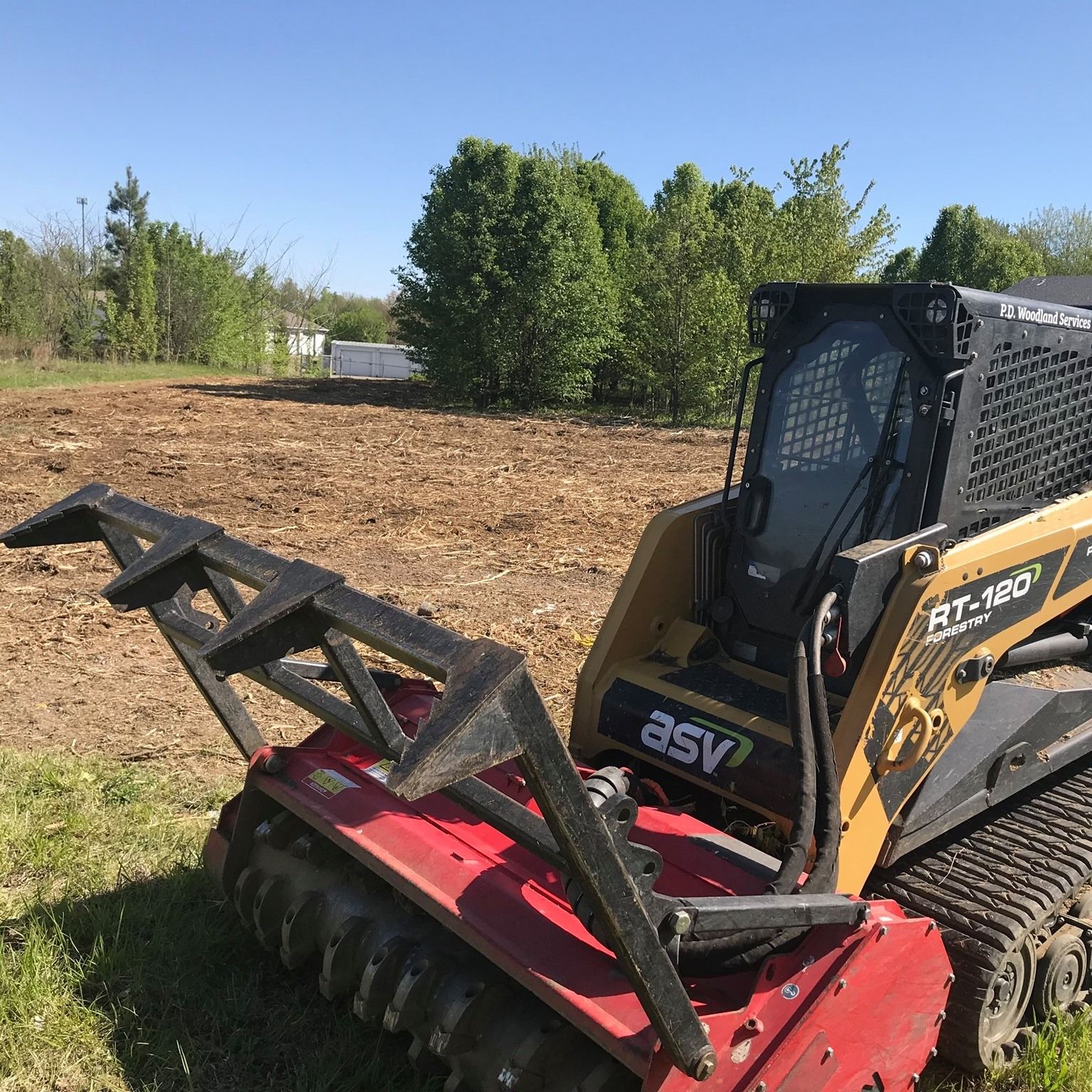 A red and black asv tractor is parked in a field