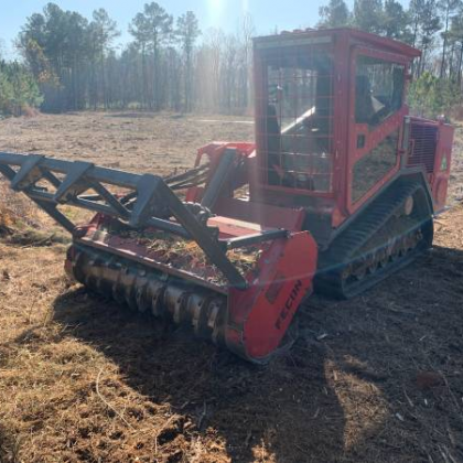 A red tractor is cutting grass in a field.
