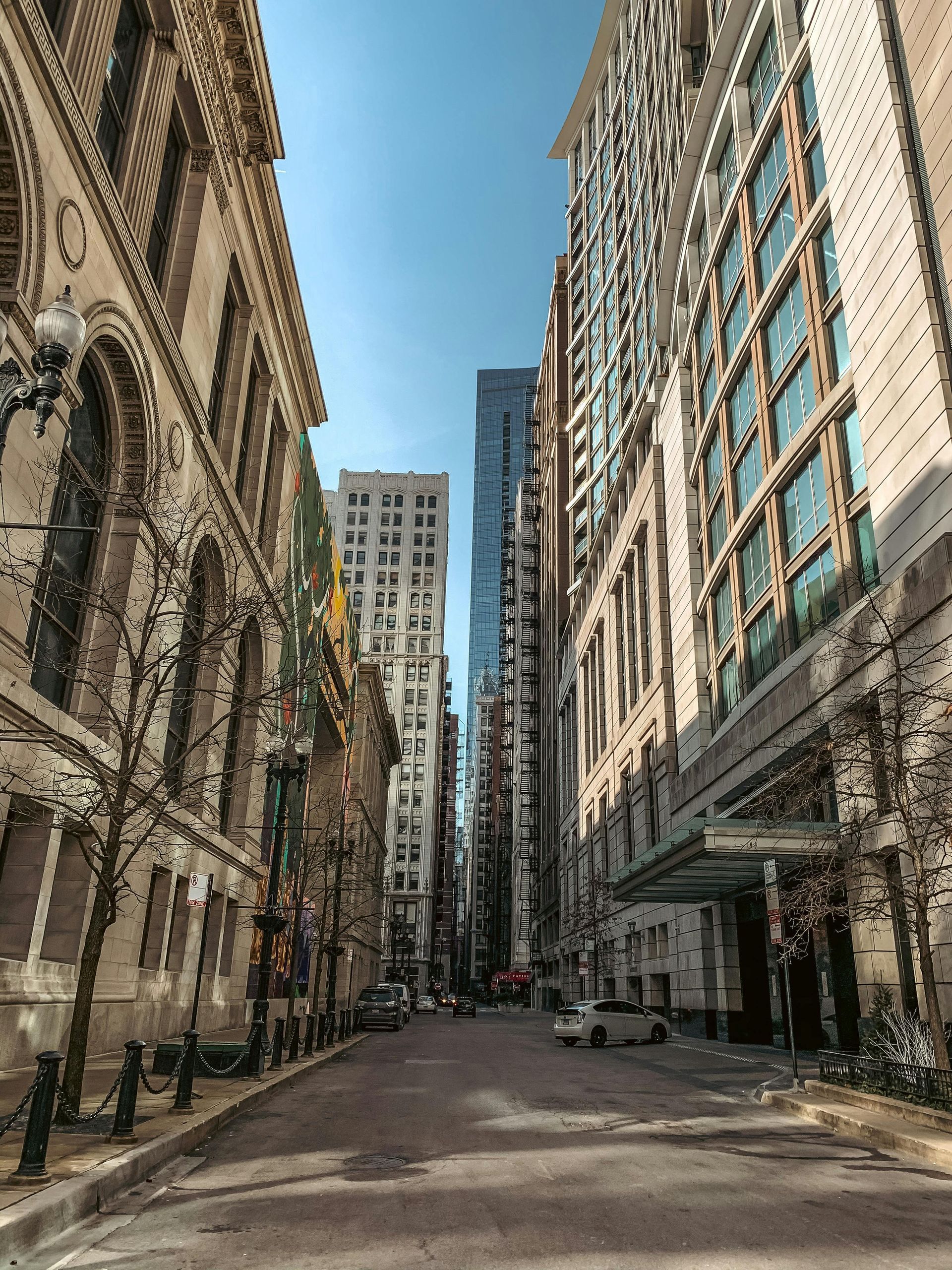 A city street lined with tall buildings on a sunny day.