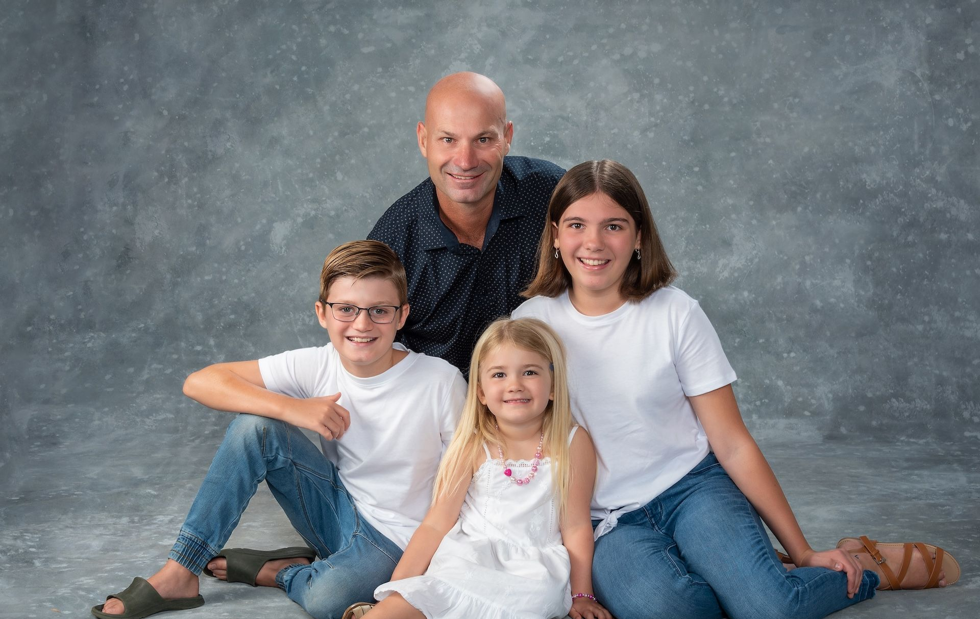 A Family is Posing for a Picture While Sitting on the Floor — Dale Wright Portrait Maker in Shepparton, VIC