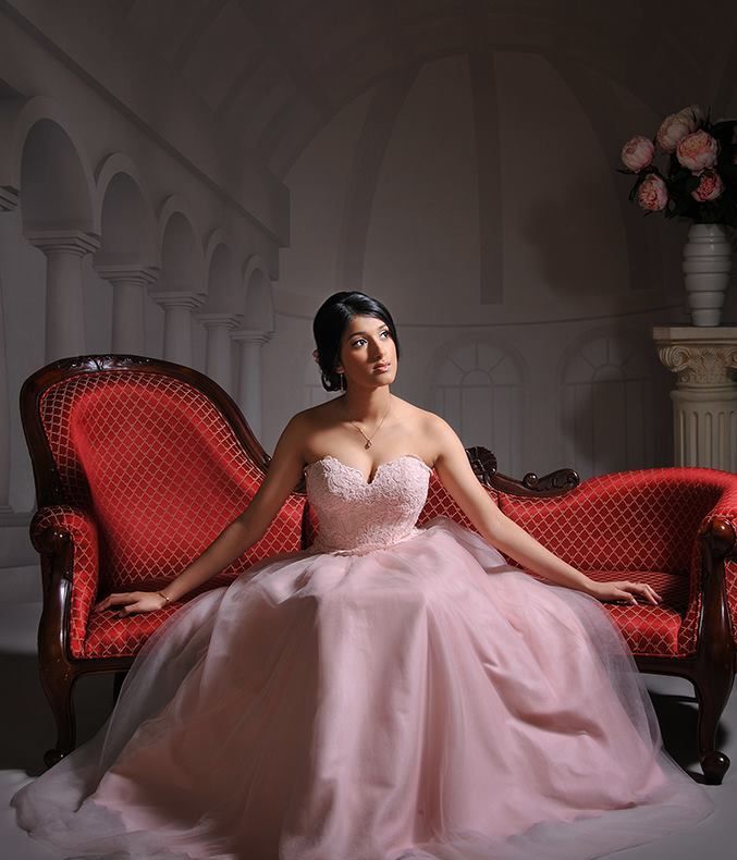 A Woman in a Pink Dress is Sitting on a Red Couch — Dale Wright Portrait Maker in Shepparton, VIC