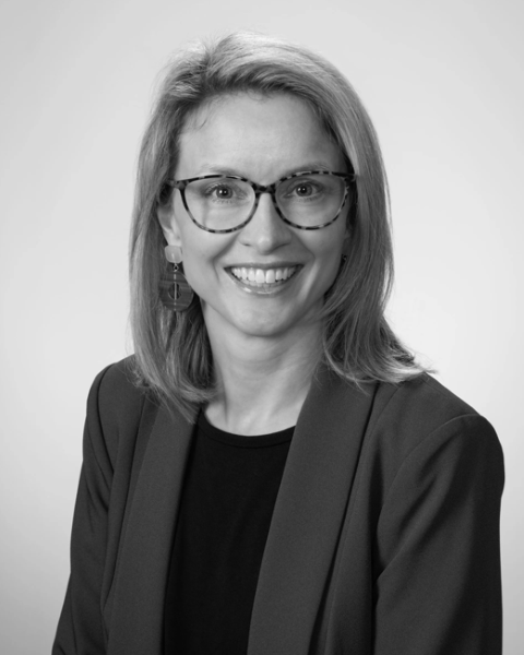A Woman Wearing Glasses and a Jacket is Smiling in a Black and White Photo — Dale Wright Portrait Maker in Shepparton, VIC