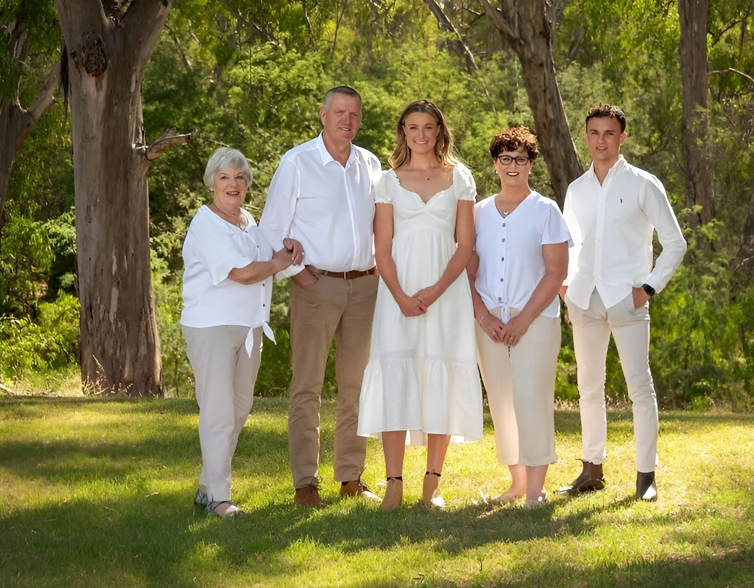 Family of five in white attire, outdoors in a park setting, smiling — Dale Wright Portrait Maker in Shepparton, VIC