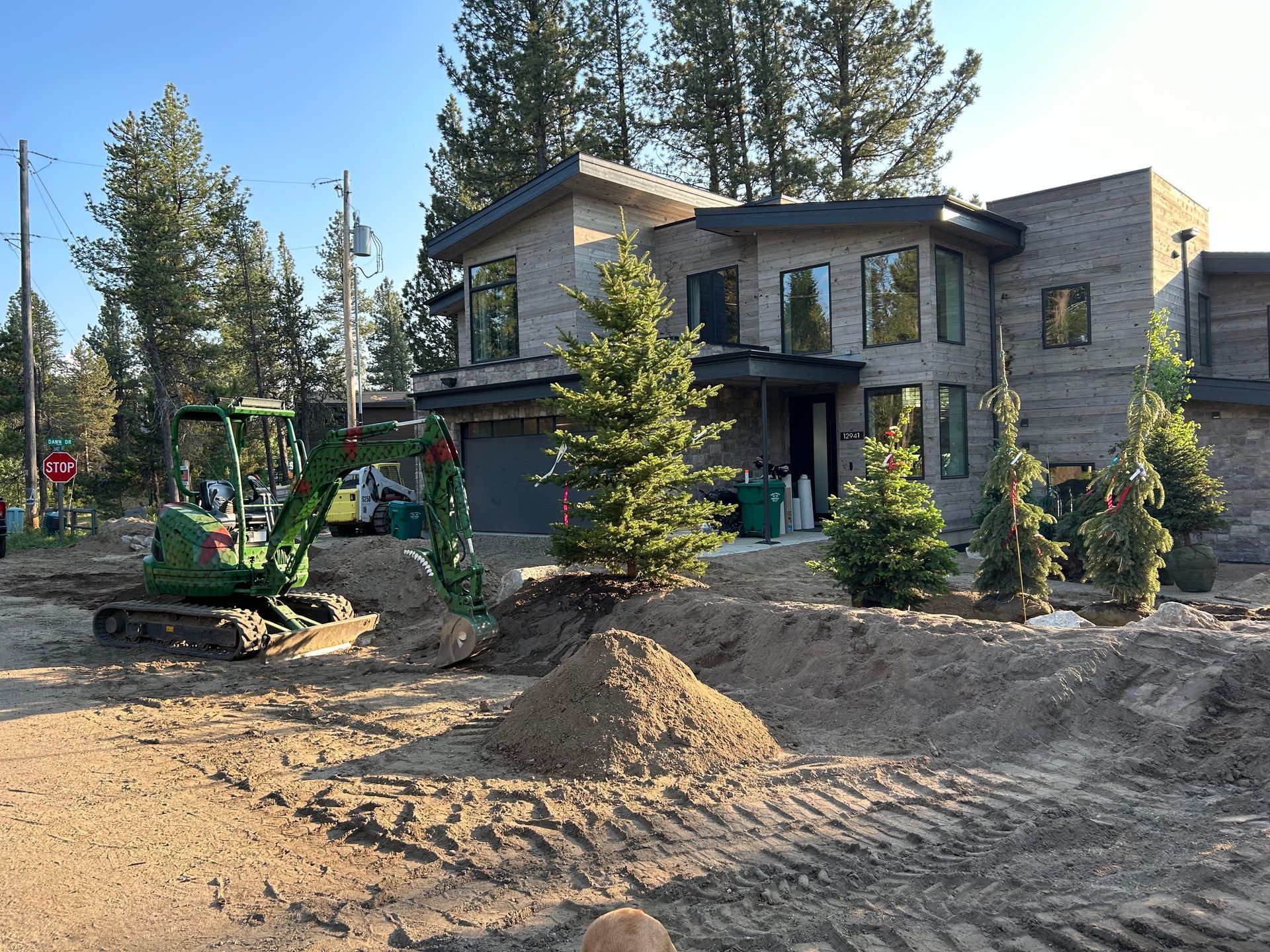 Construction site with excavator, bulldozer, and tractor moving dirt under a blue sky.