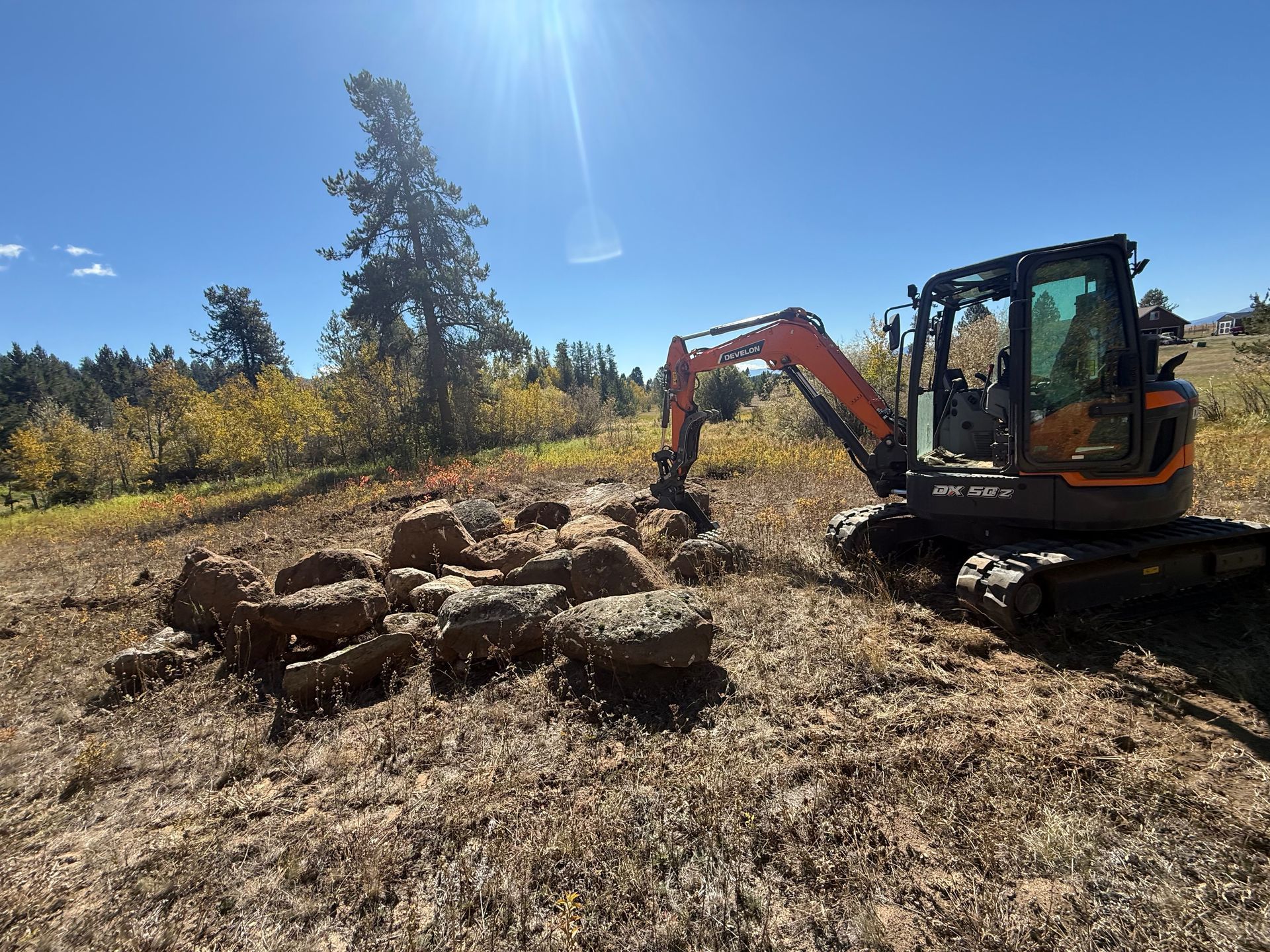 Yellow bulldozer clearing land, with trees in the background.