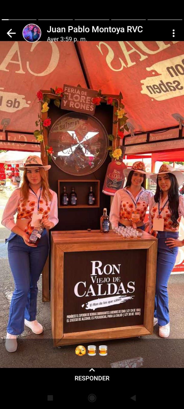 Un grupo de mujeres de pie alrededor de una mesa con un cartel que dice ron de caldas.