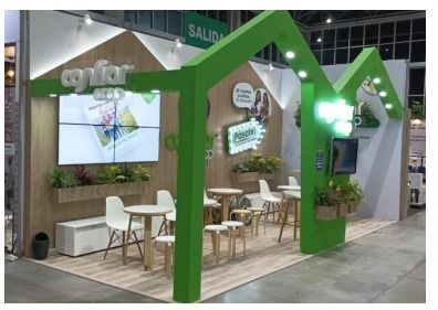 Un stand verde con mesas y sillas en forma de casa.