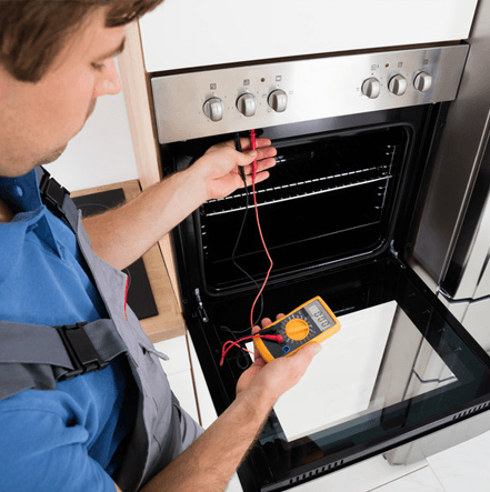 Young Male Technician Checking Oven With Digital Multimeter