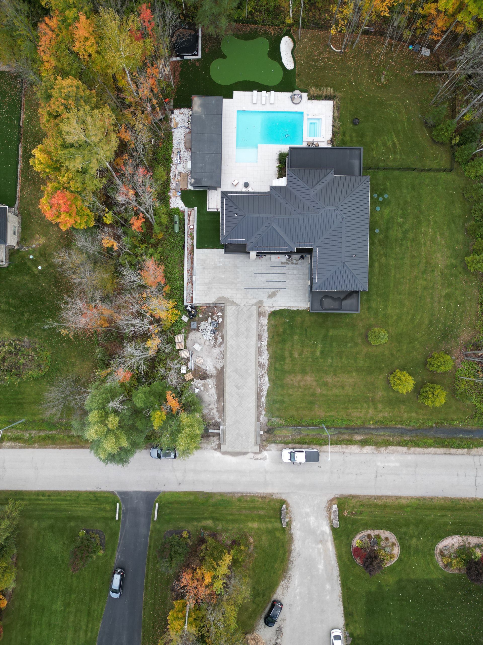 An aerial view of a house with a pool in the backyard surrounded by trees.