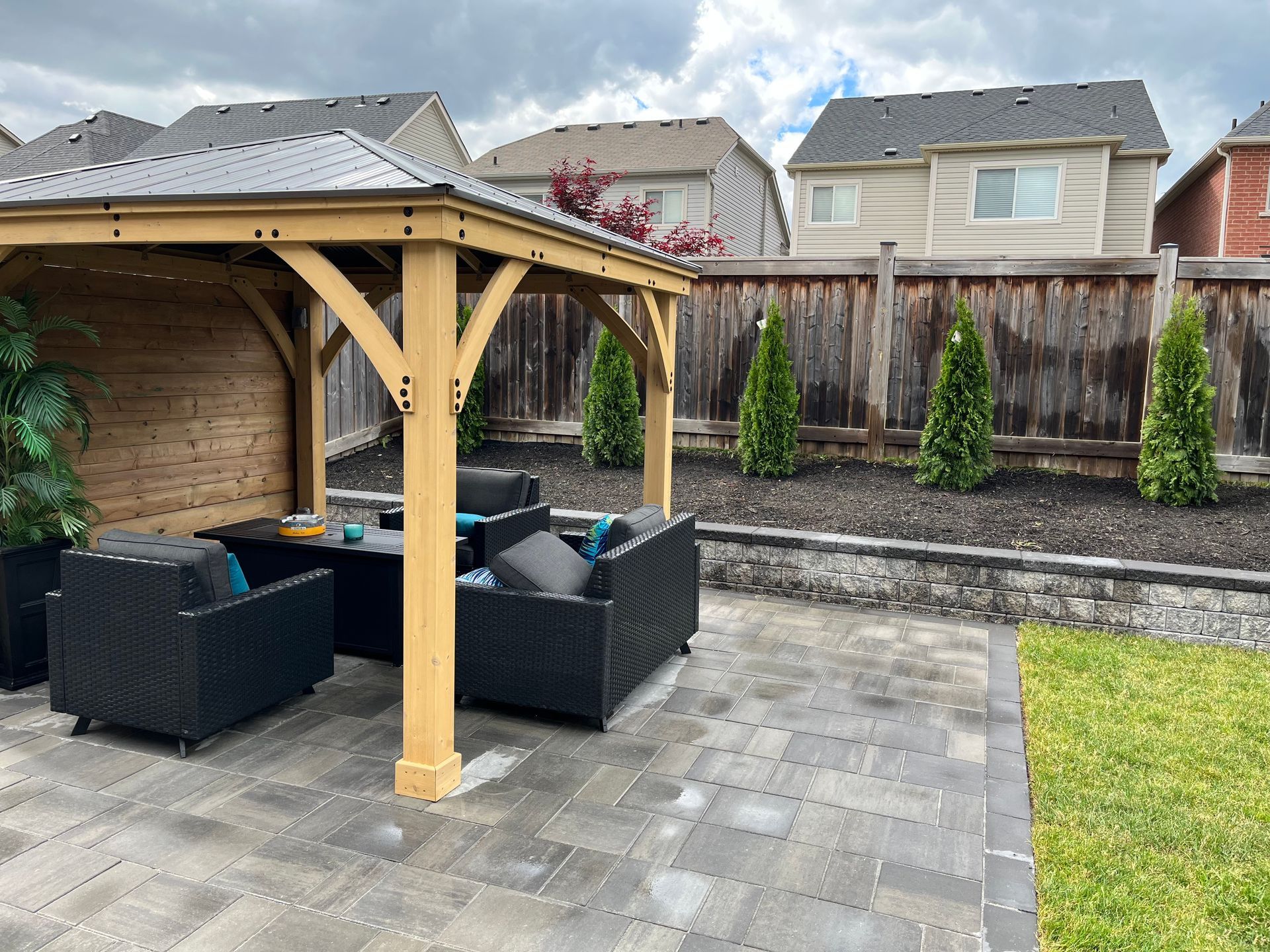 A backyard with a wooden gazebo and patio furniture.