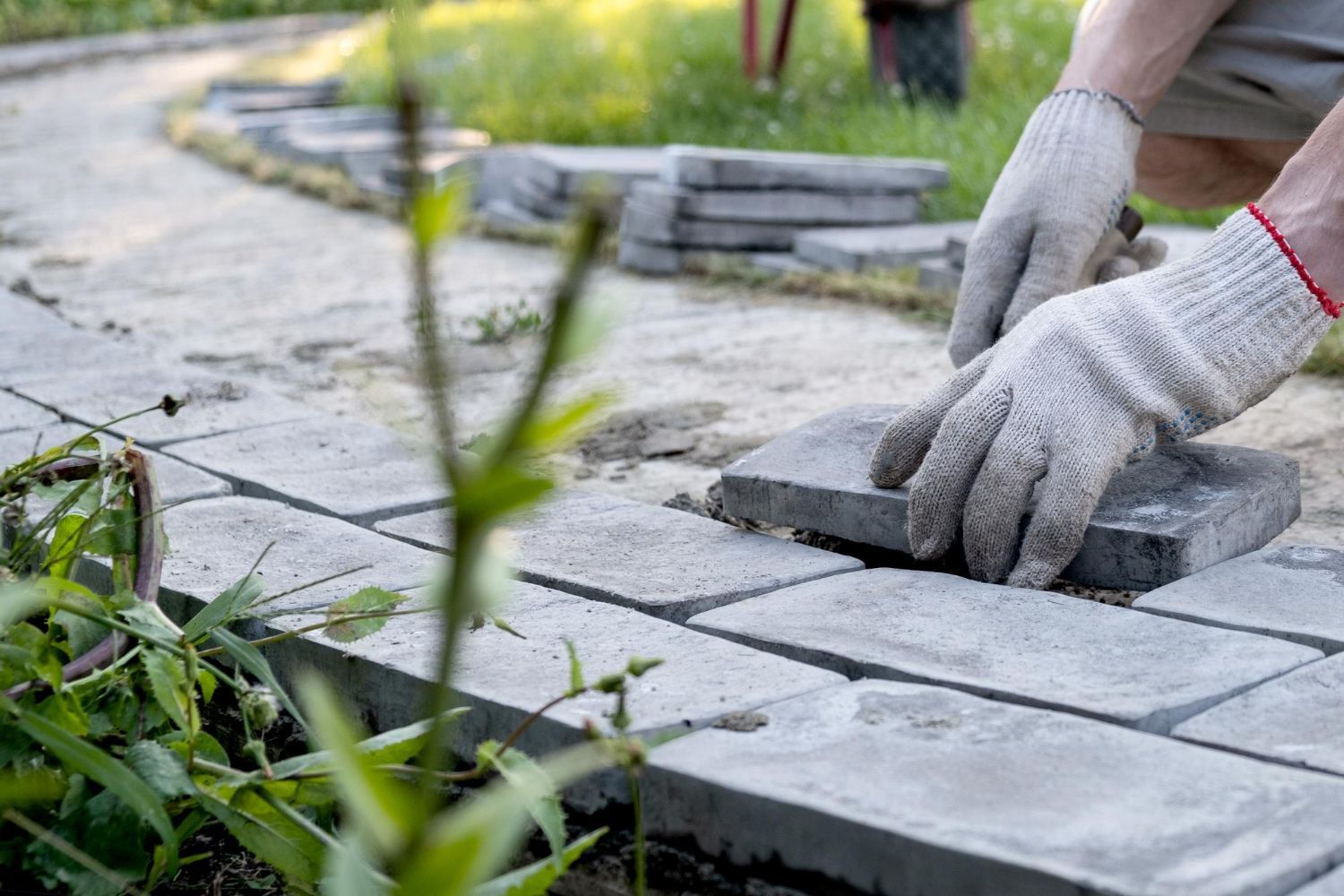 A person is putting bricks on a sidewalk.