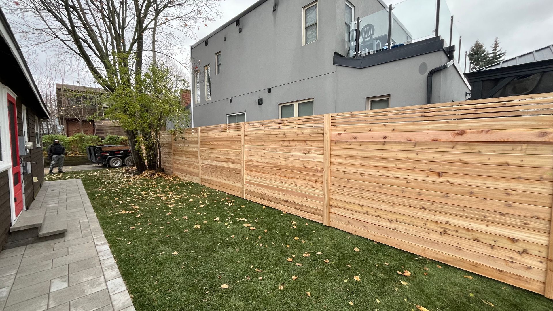 A wooden fence is in the backyard of a house.