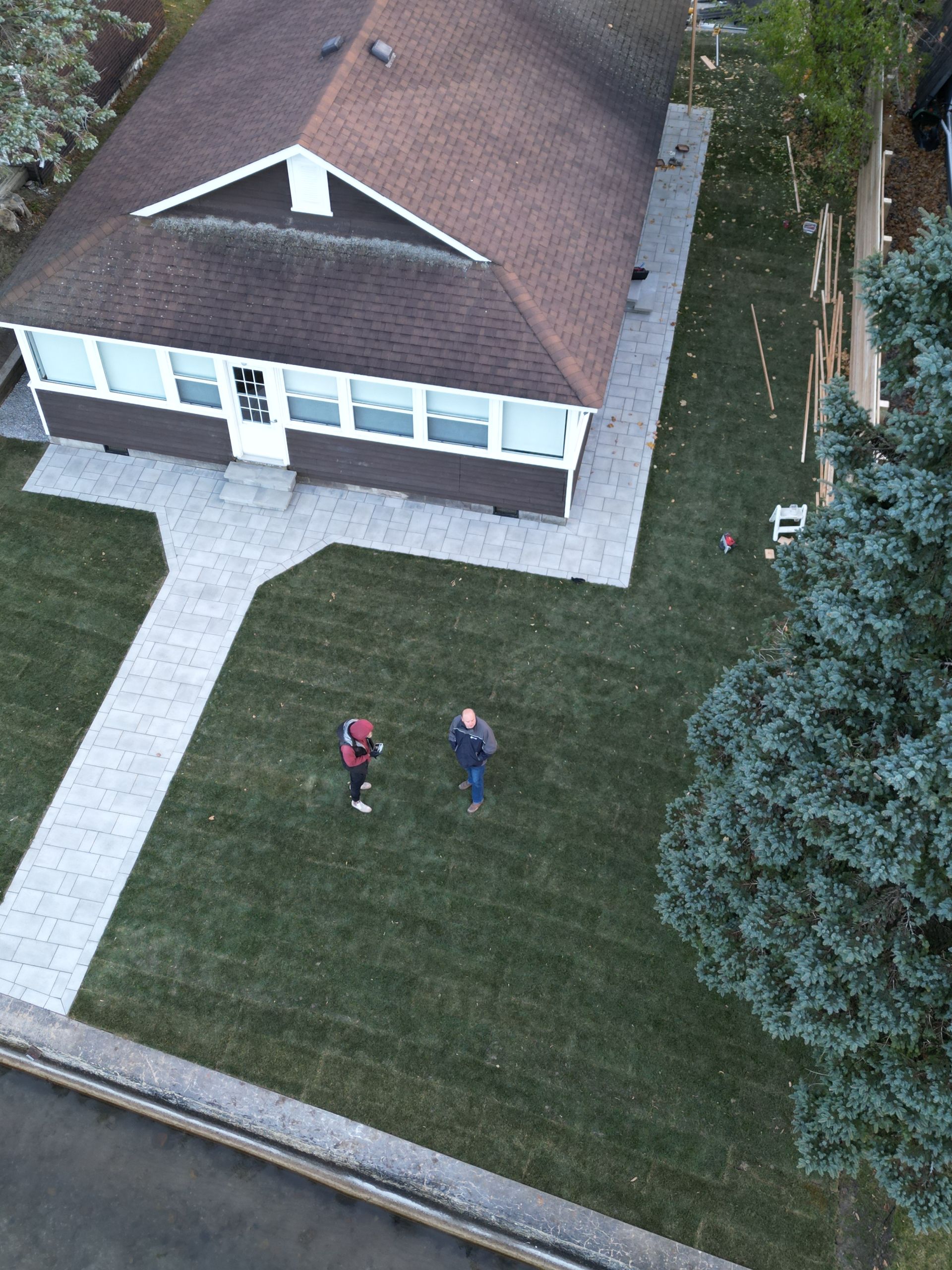 An aerial view of two people standing in front of a house