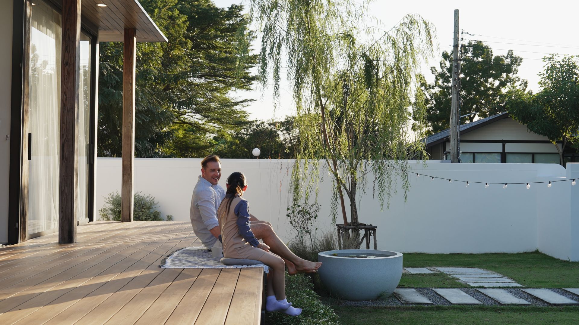 A man and a woman are sitting on a deck in front of a house.