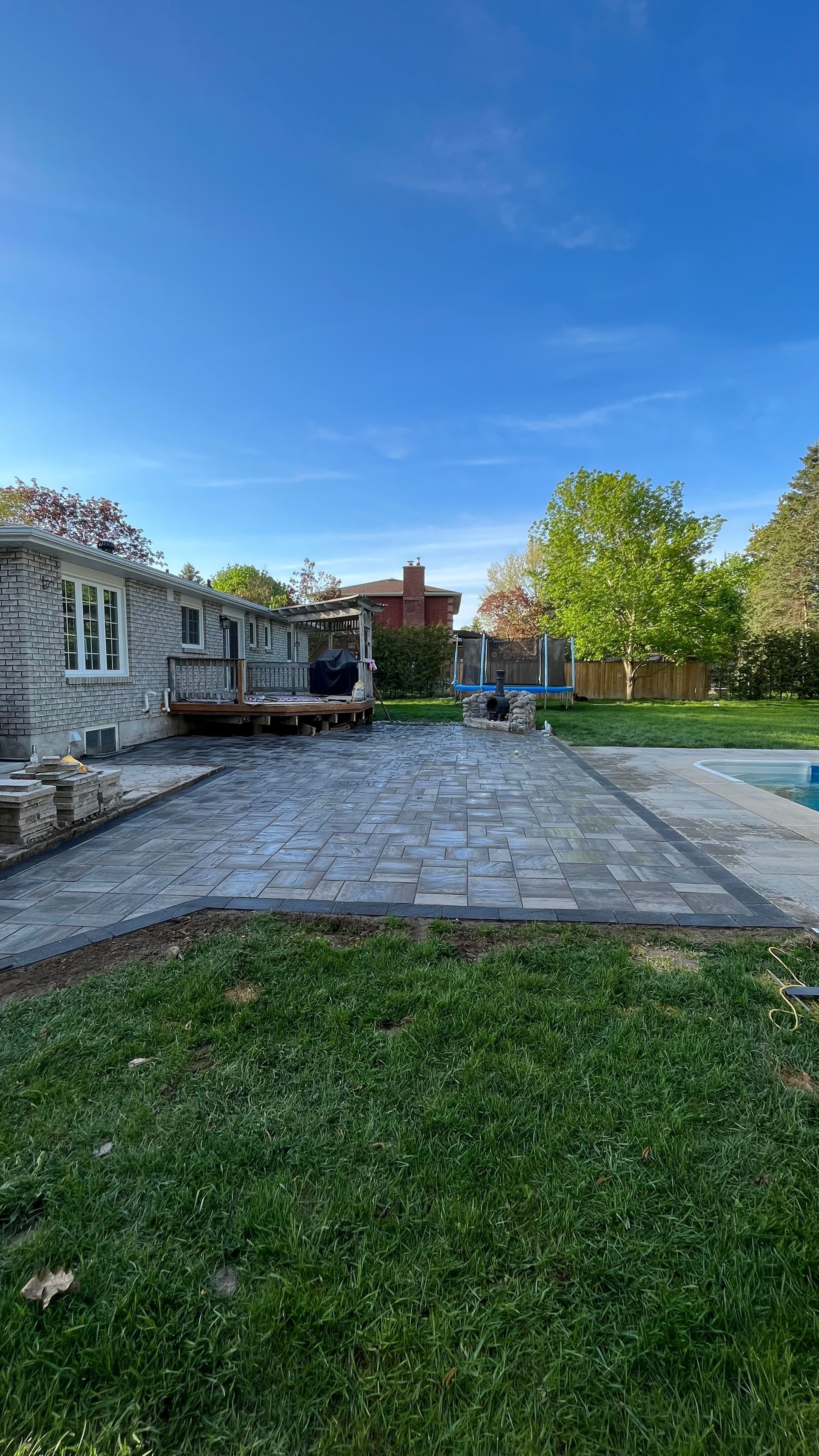 a backyard with a patio and a pool in front of a house .
