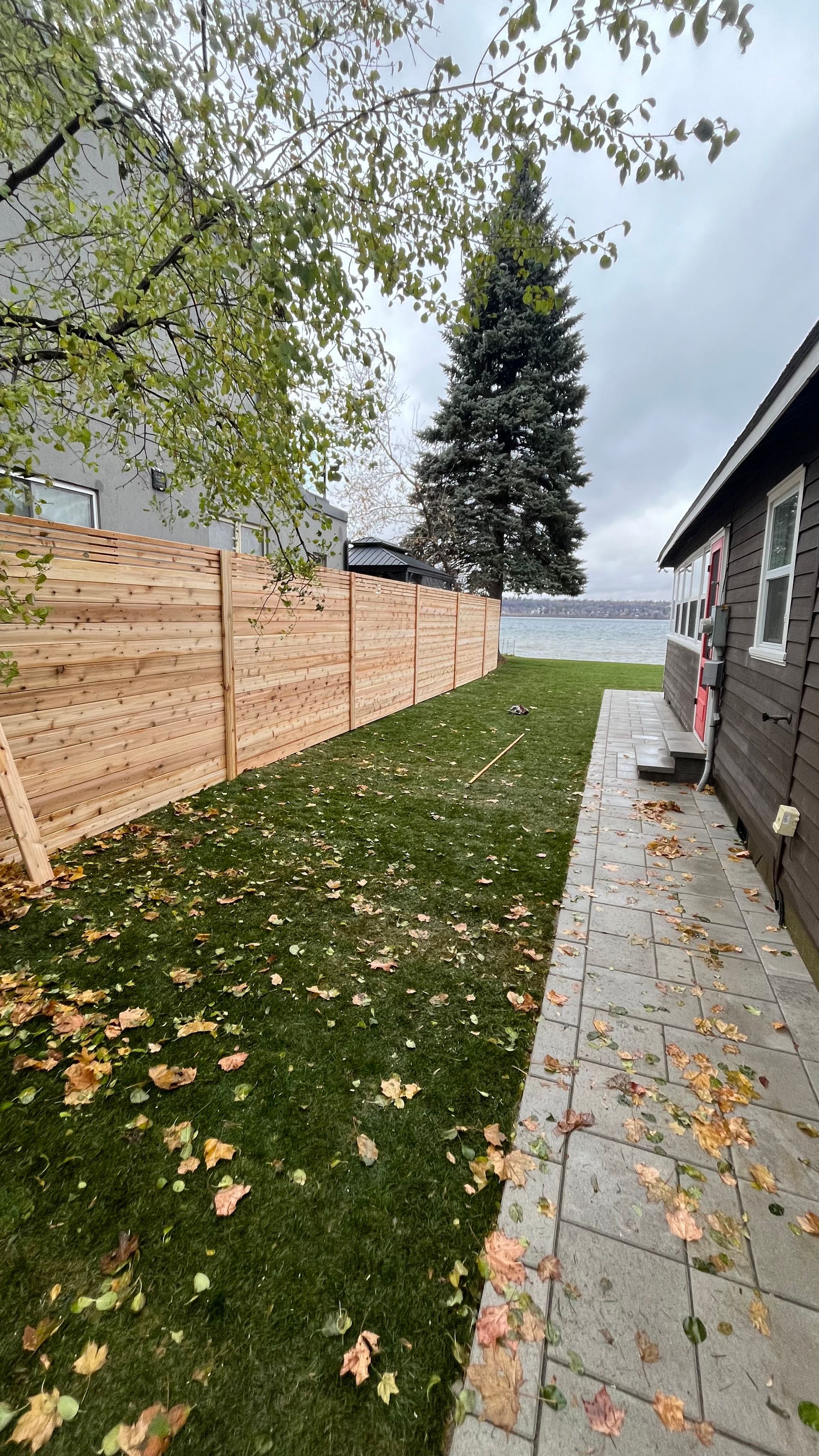 a wooden fence surrounds a lush green yard next to a house .