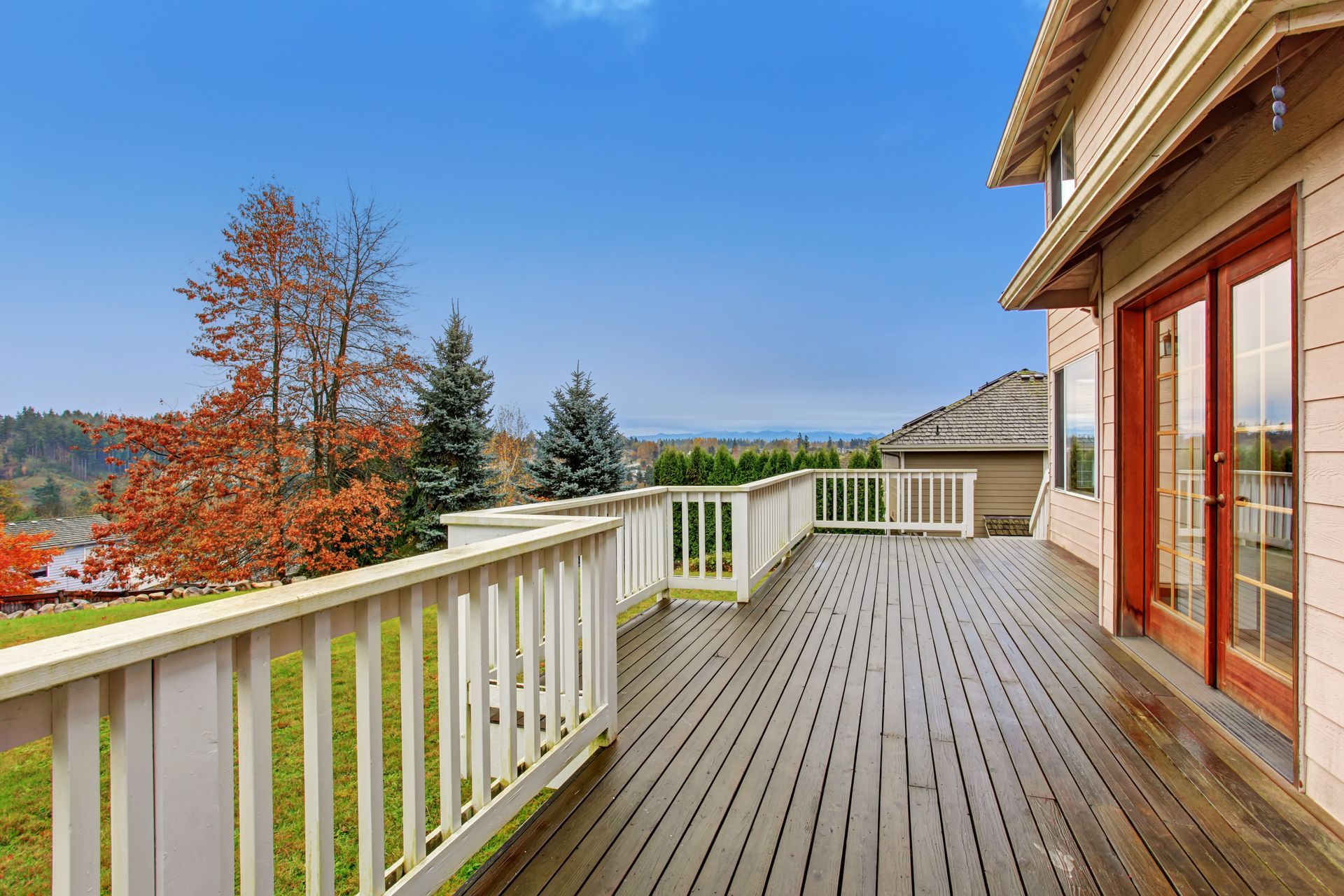a large wooden deck with a white railing and sliding glass doors .