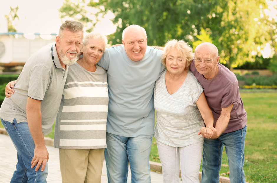 A group of elderly people are posing for a picture in a park.