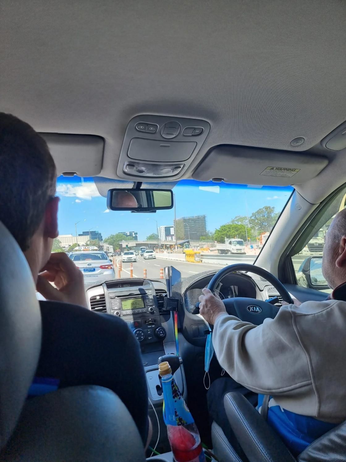 Inside a Car: Driver and Passenger, City Street Visible Through Windshield — Dave's Drive U Anywhere 24/7 Mini Van Hire In Shellharbour, NSW