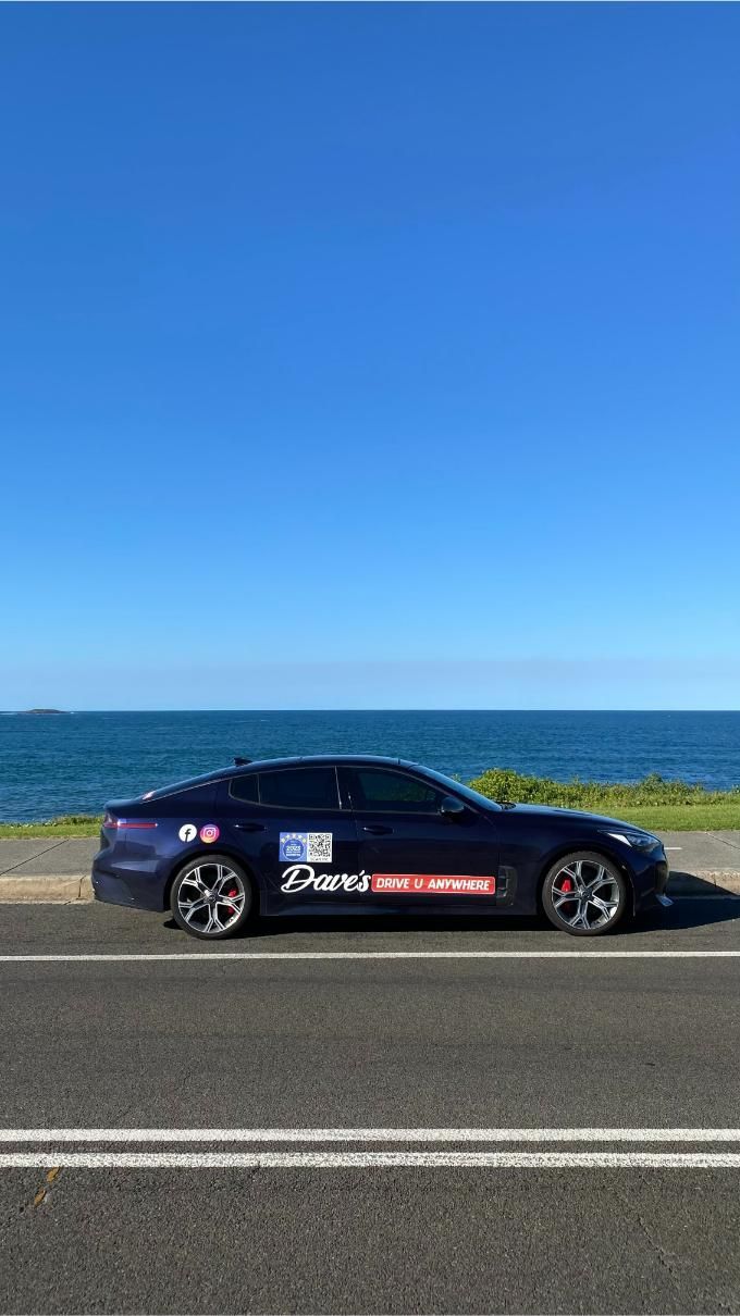 Dark Blue Car Parked by the Ocean, With Stickers Visible on the Side — Dave's Drive U Anywhere 24/7 Mini Van Hire In Albion Park, NSW