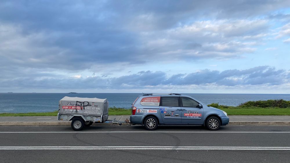 Blue Car Towing a White Trailer — Dave's Drive U Anywhere 24/7 Mini Van Hire In Wollongong, NSW
