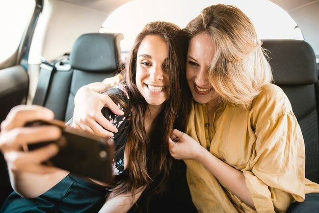 Two Smiling Women Take a Selfie Inside a Car — Dave's Drive U Anywhere 24/7 Mini Van Hire In Wollongong, NSW