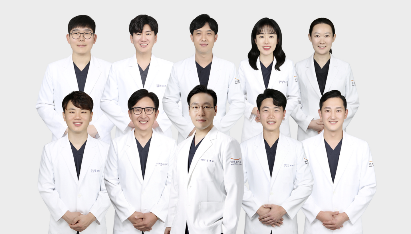 Group of ten people wearing white lab coats smiling for a photo.