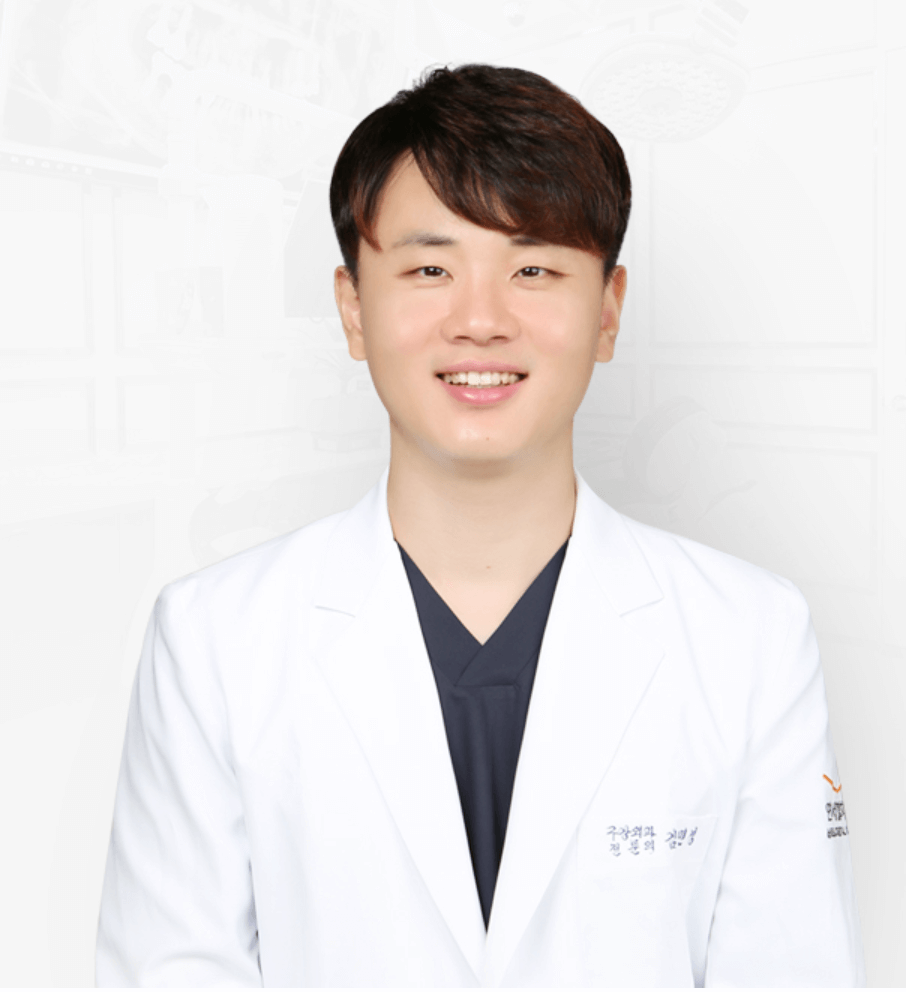 Smiling Asian man in white lab coat, dark top. Studio shot.