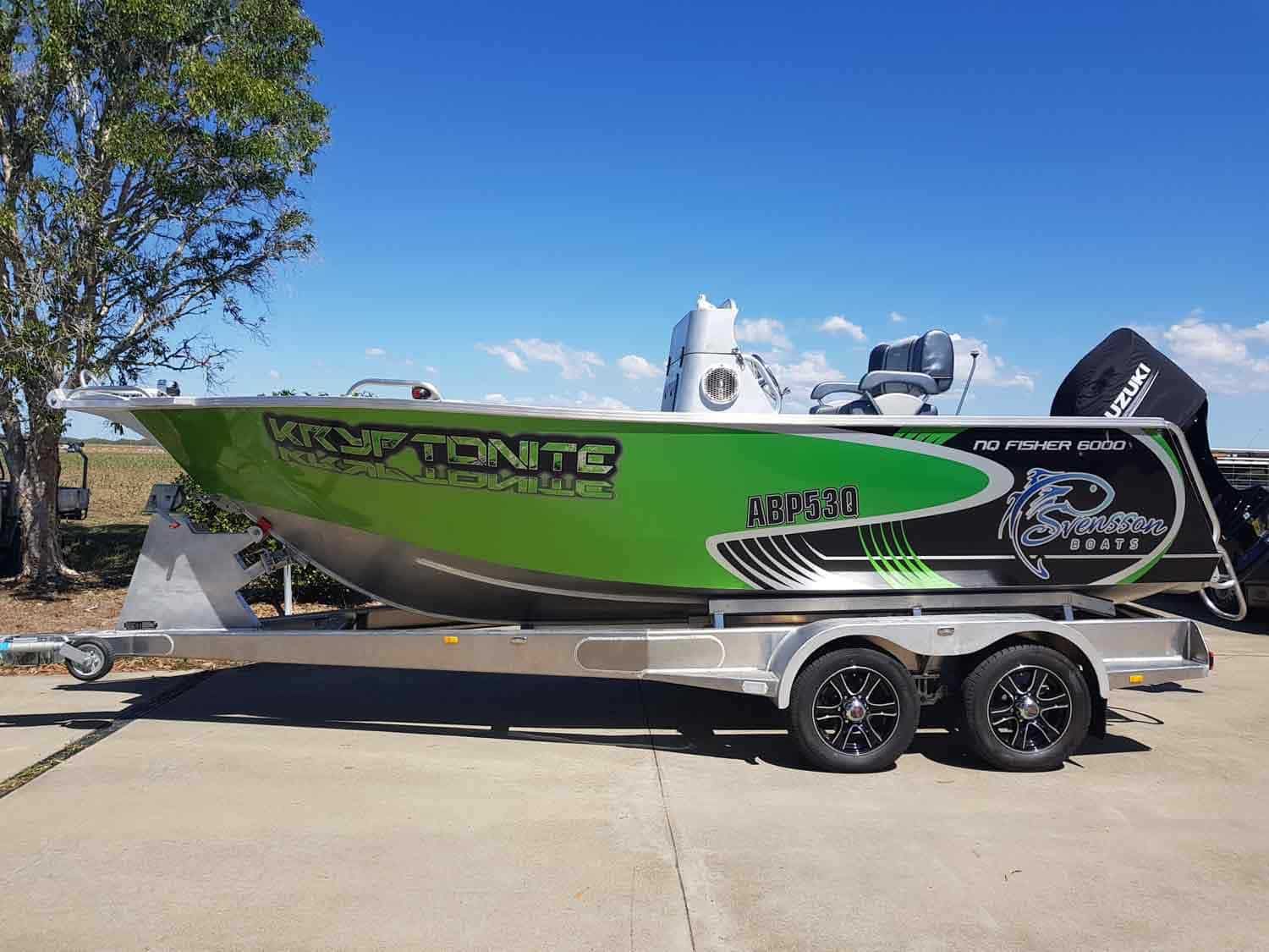 A green and black boat is parked on a trailer  — Sun City Signs In Moranbah, QLD