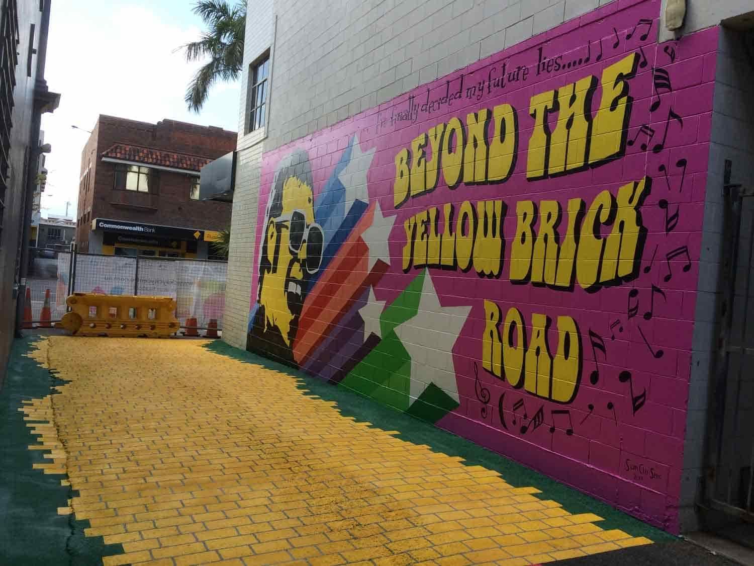A Mural On The Side Of A Building That Says Beyond The Yellow Brick Road — Sun City Signs In Paget, QLD