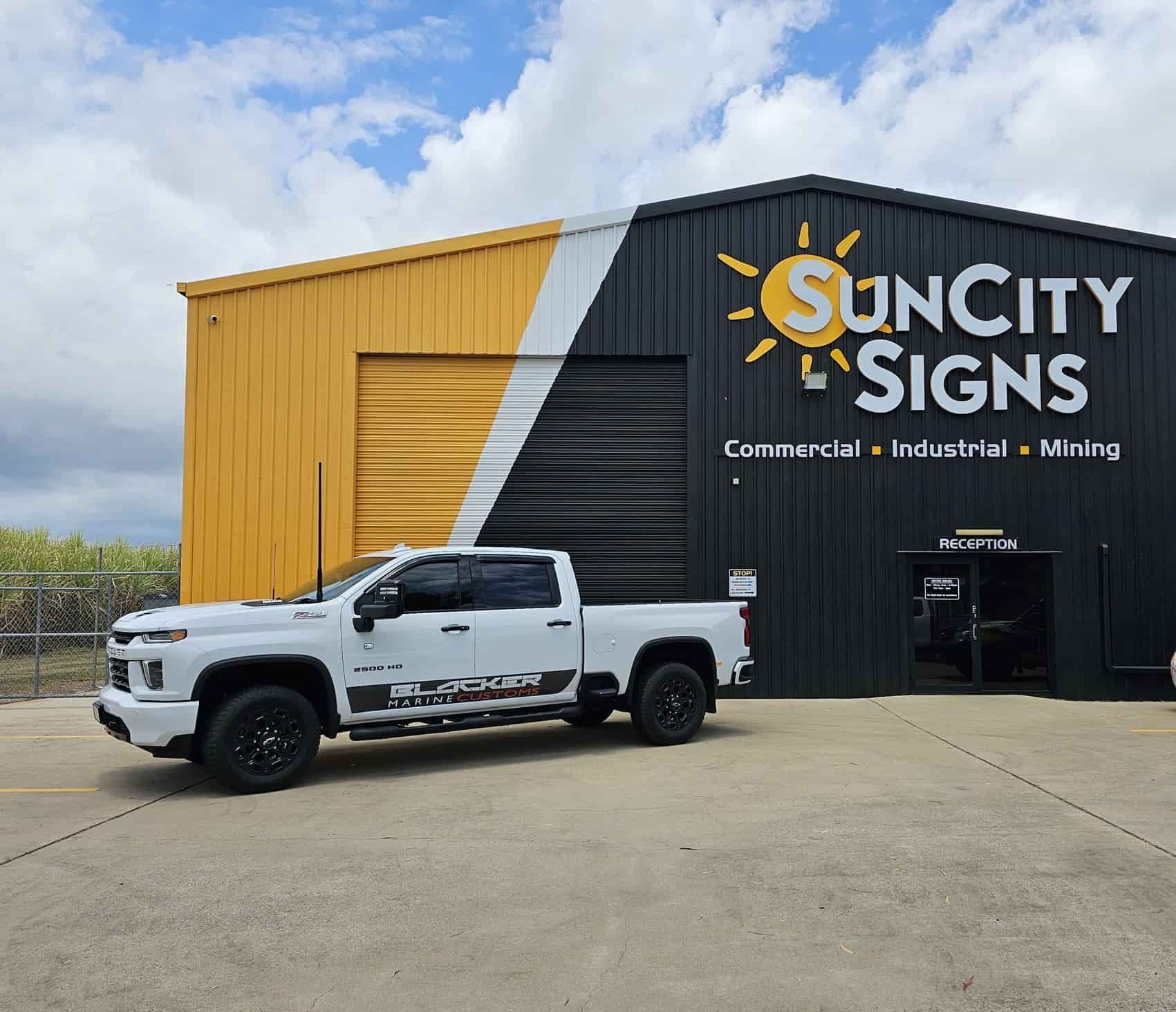 A White Truck Is Parked In Front Of A Sun City Signs Building — Sun City Signs In Paget, QLD