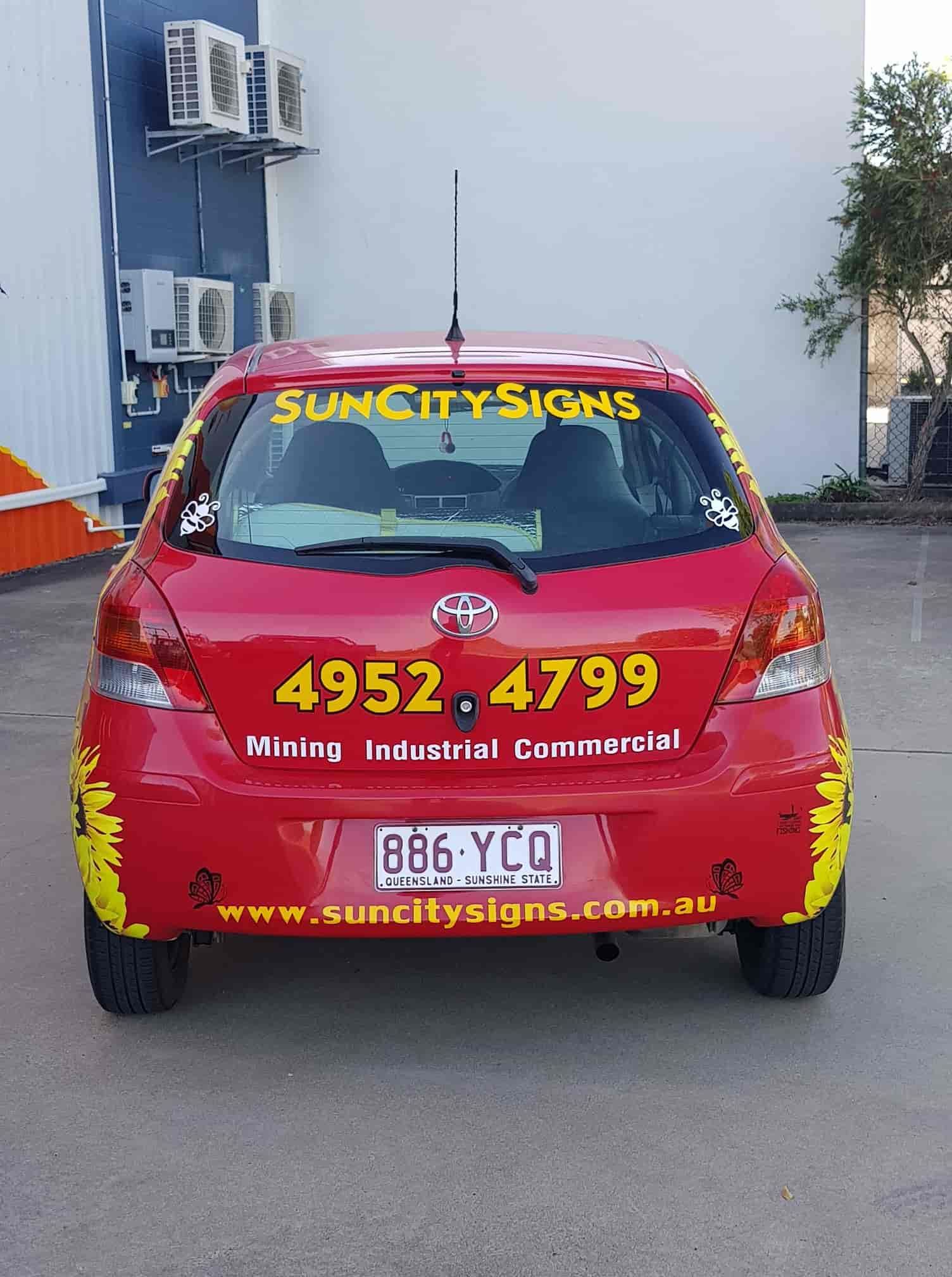 A Red Car With A Yellow Sticker On The Back That Says Sun City Signs — Sun City Signs In Paget, QLD