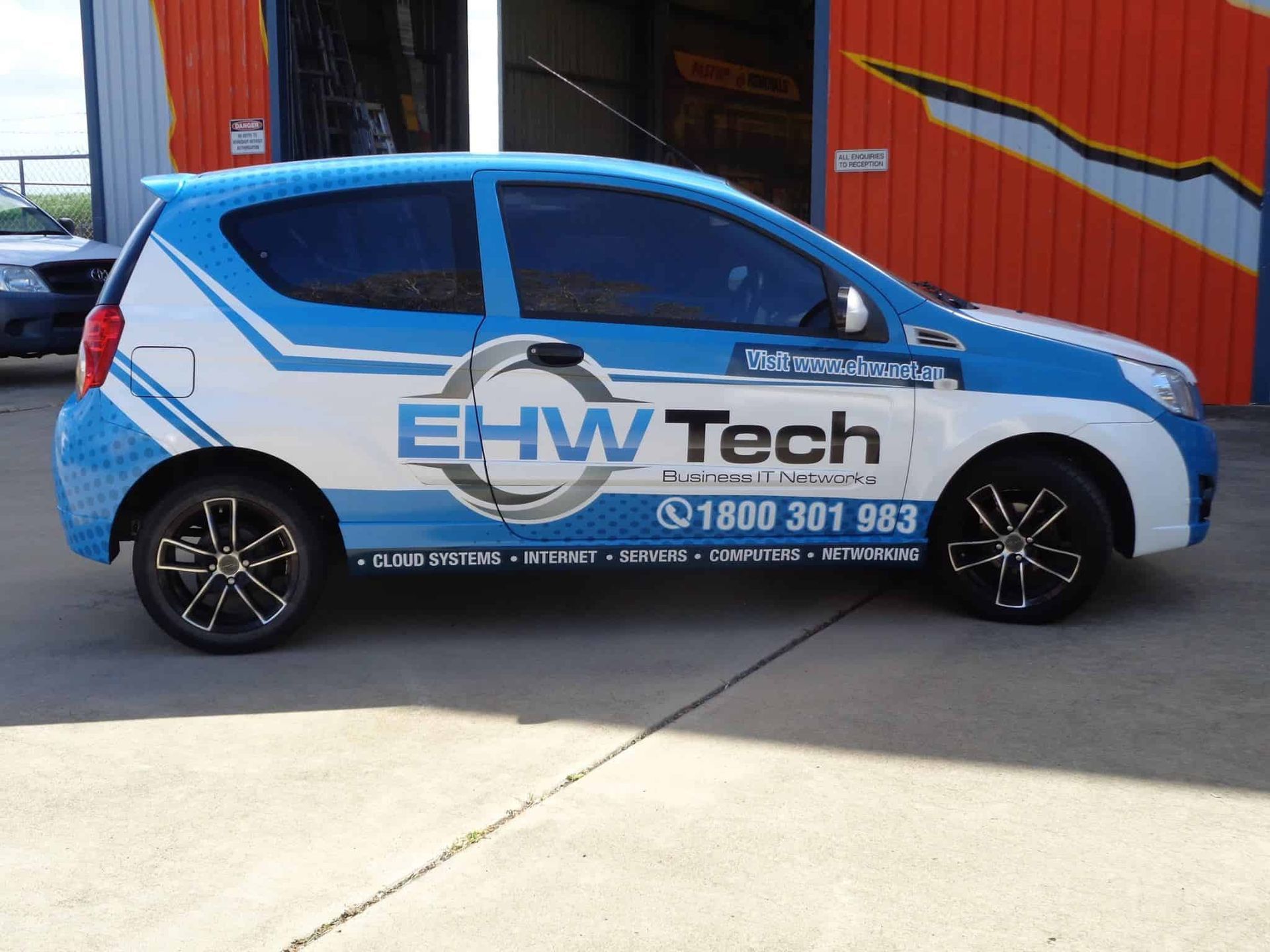 A Blue And White Ehw Tech Car Is Parked In Front Of A Building — Sun City Signs In Paget, QLD