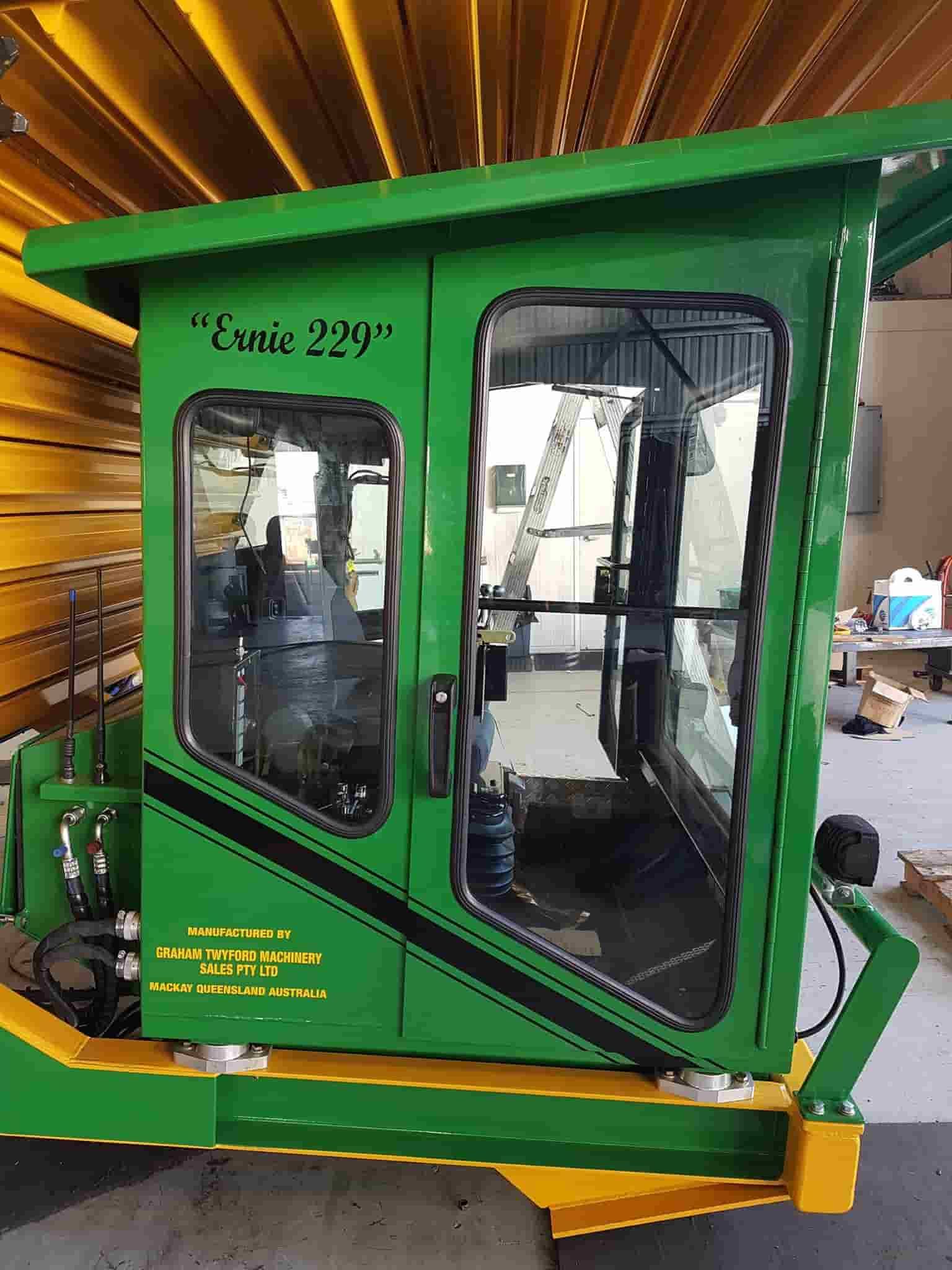 A Green And Yellow Tractor Cab Is Sitting In A Room — Sun City Signs In Moranbah, QLD