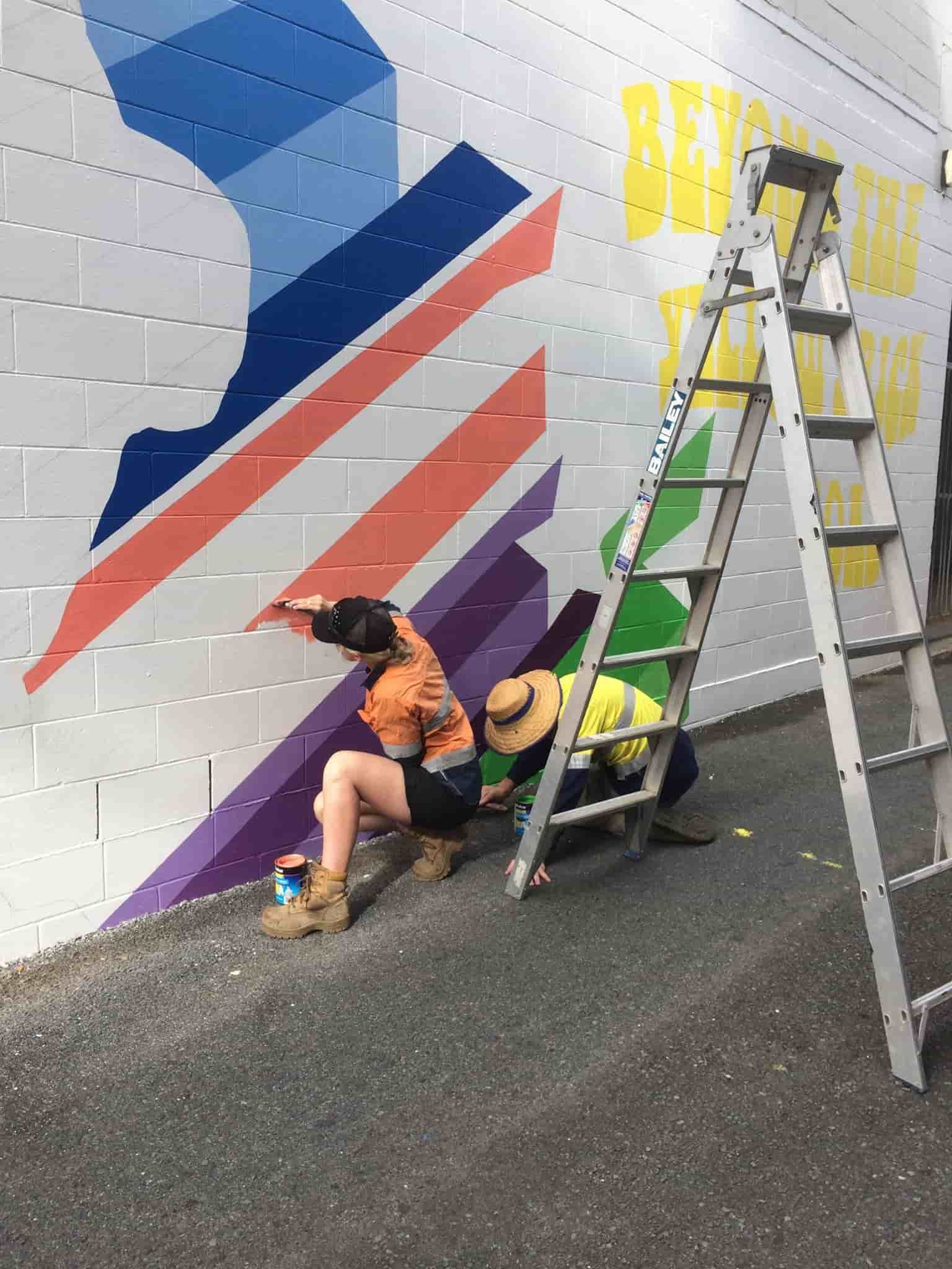 A Group Of People Are Painting A Mural On A Brick Wall — Sun City Signs In Sarina, QLD