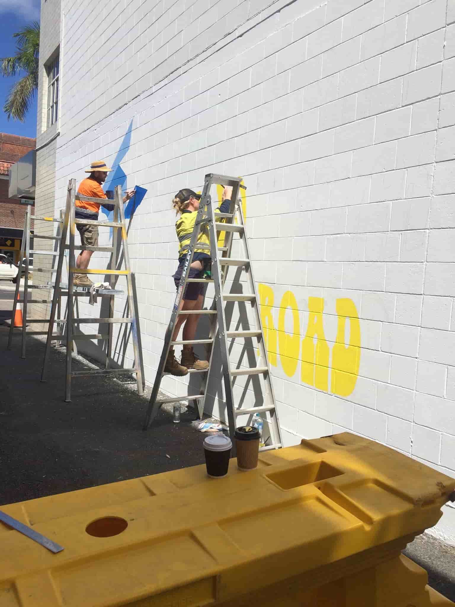 A Group Of People Are Painting A Mural On The Side Of A Building — Sun City Signs In Sarina, QLD