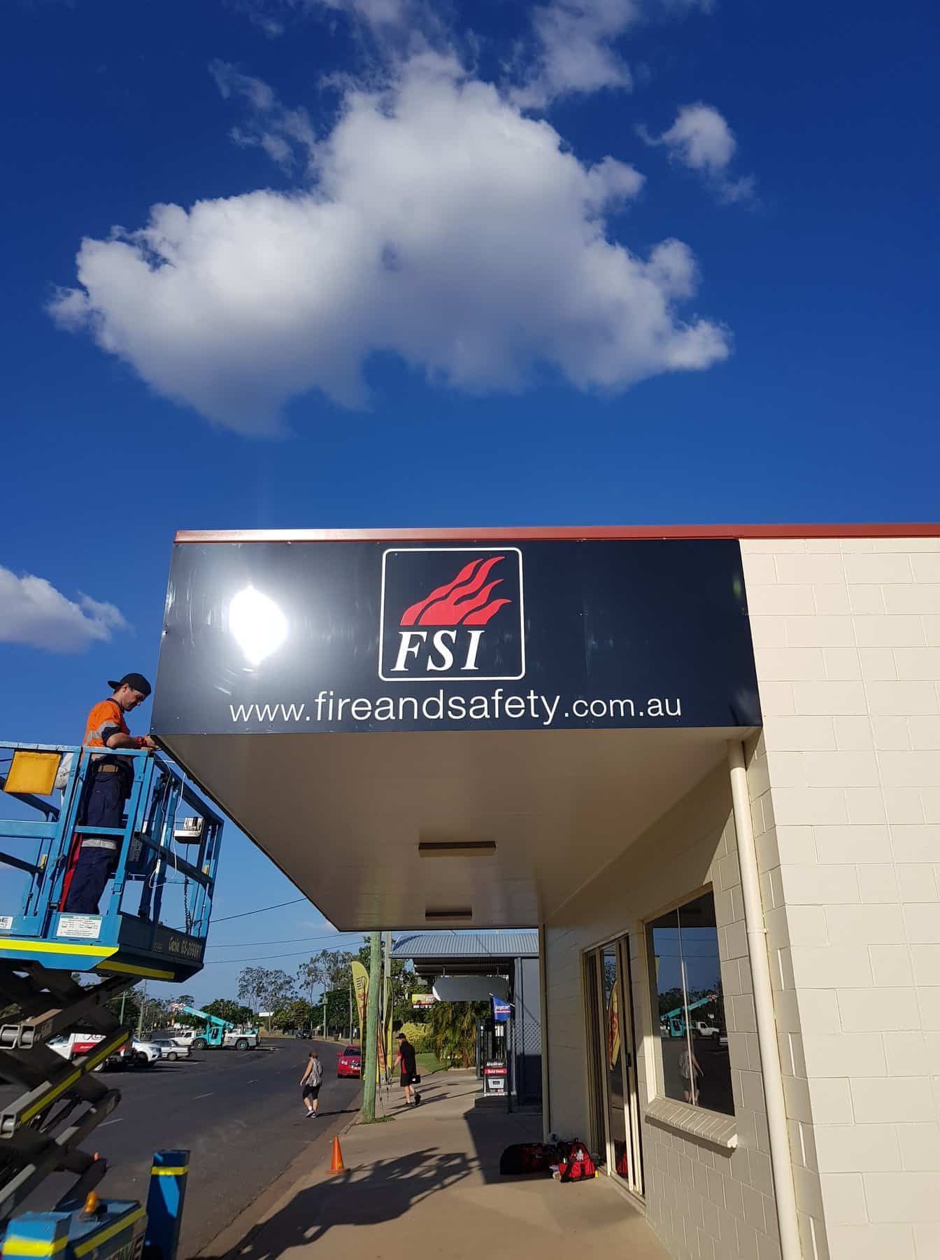 A Man Is Working On A Sign On The Side Of A Building — Sun City Signs In Moranbah, QLD