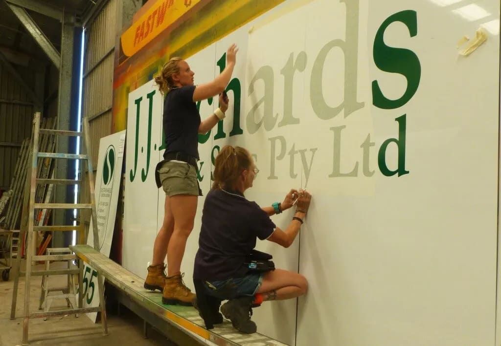 Two Women Are Working On A Large Sign That Says Pty Ltd — Sun City Signs In Paget, QLD