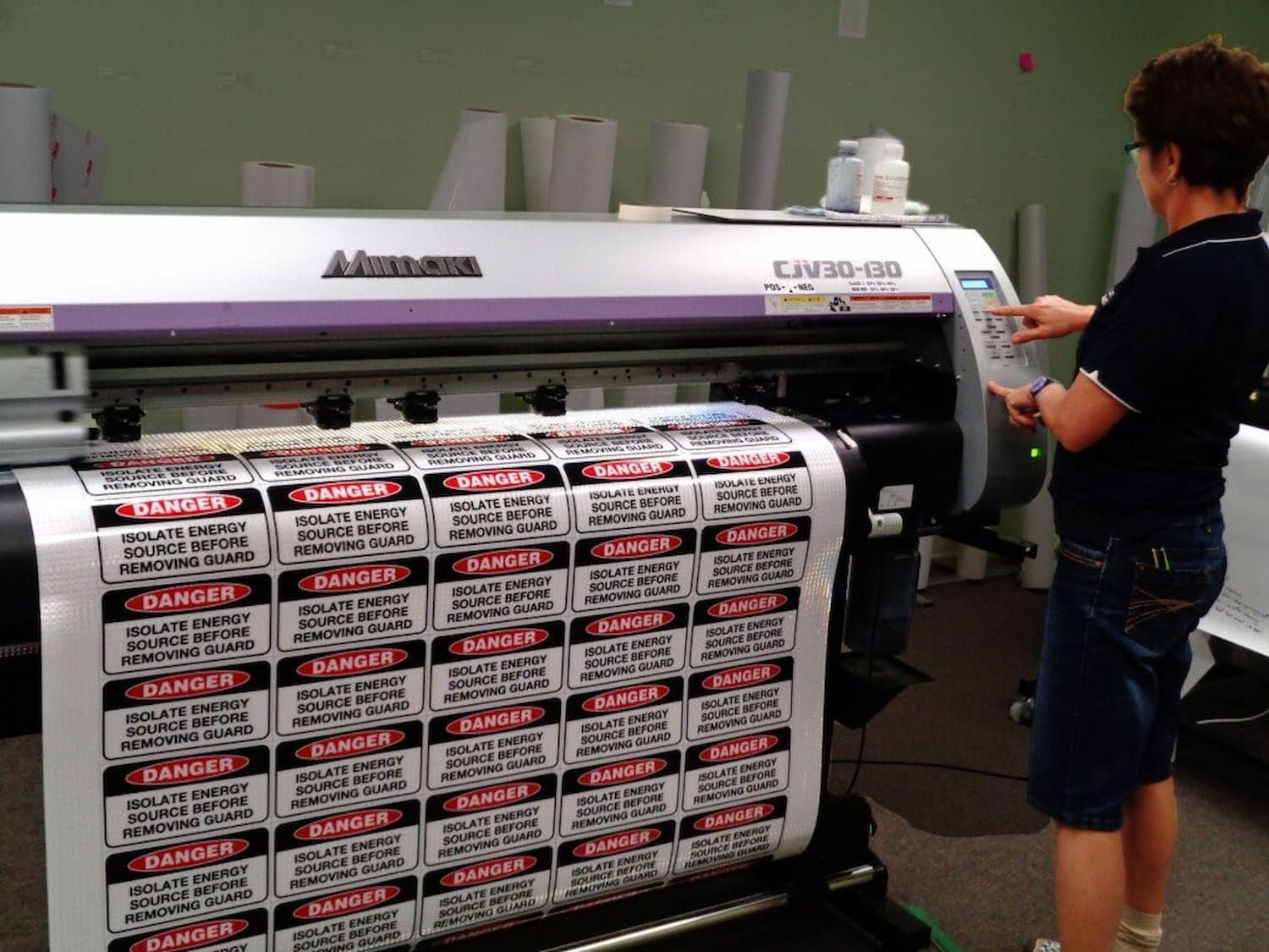 A Man Is Standing In Front Of A Machine That Has A Lot Of Labels On It — Sun City Signs In Paget, QLD
