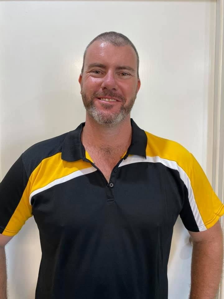 A Man Wearing A Black And Yellow Polo Shirt Is Standing In Front Of A White Wall — Sun City Signs In Paget, QLD