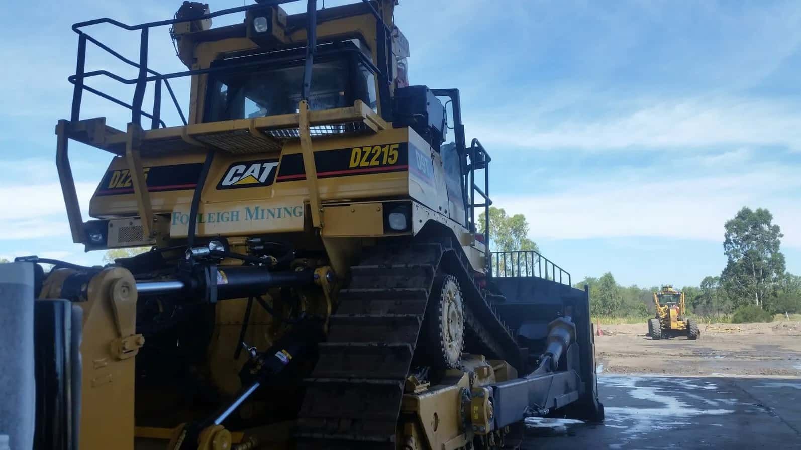 A Large Yellow Cat Bulldozer Is Parked In A Field — Sun City Signs In Moranbah, QLD
