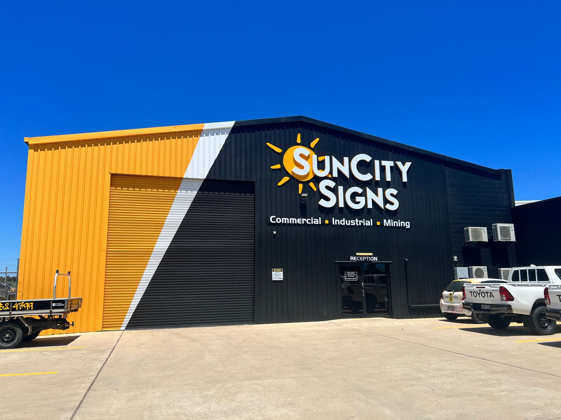 A sun City Signs Building With Cars Parked in Front of it  — Sun City Signs In Paget, QLD