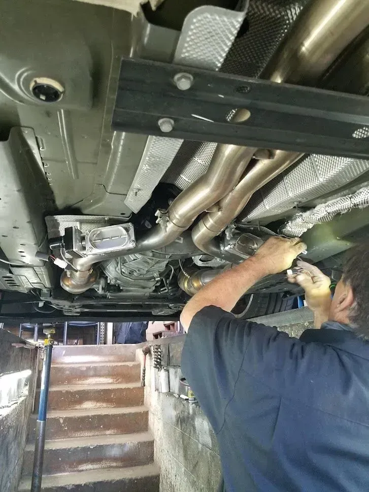 A man is working on the underside of a car | Ed Hanson's Muffler Service