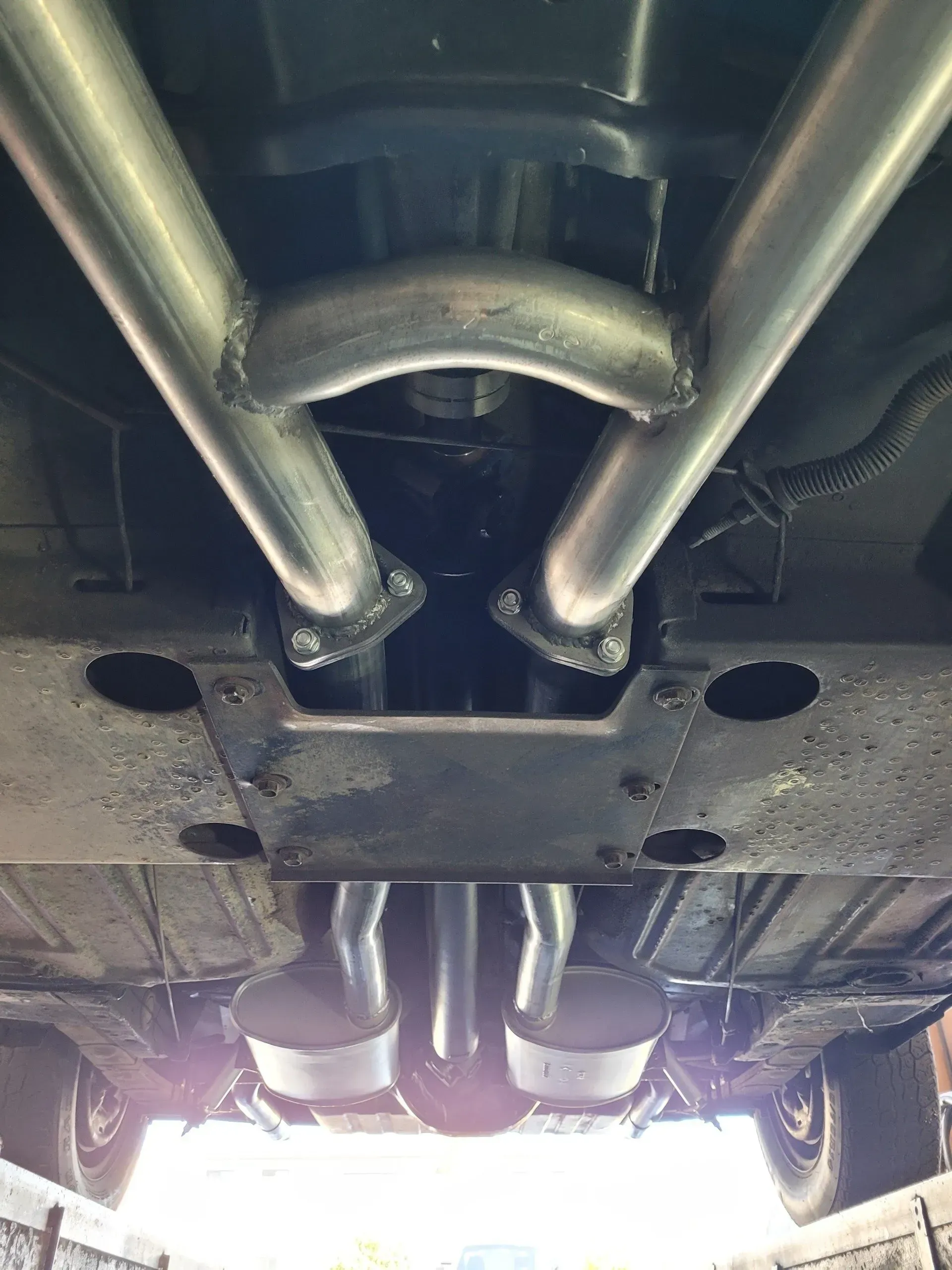 A close up of the underside of a car with exhaust pipes | Ed Hanson's Muffler Service