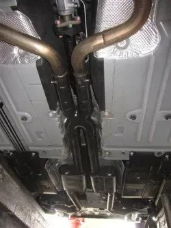 A close up of the underside of a car with exhaust pipes | Ed Hanson's Muffler Service