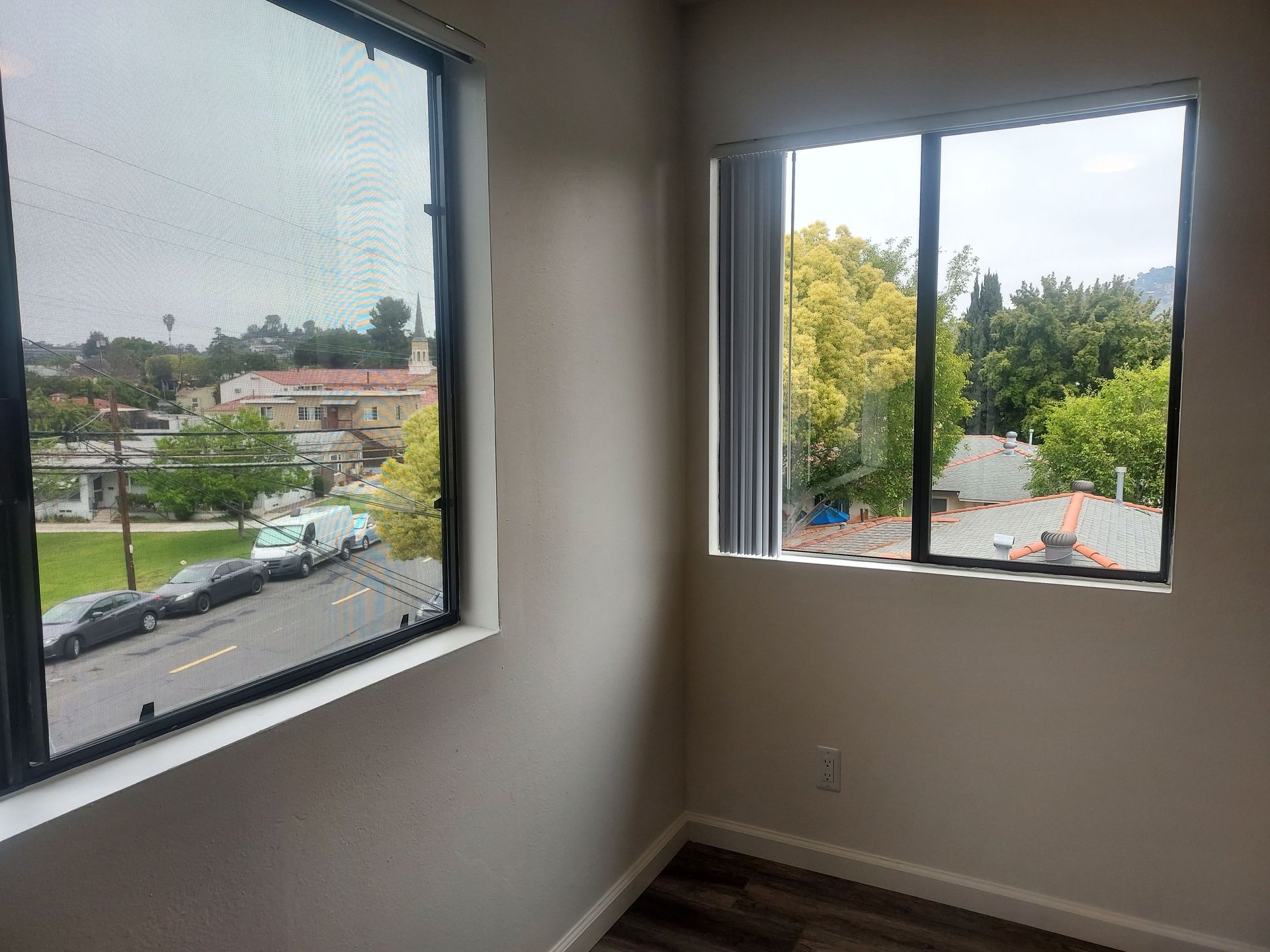 A room with two windows and a view of a city.