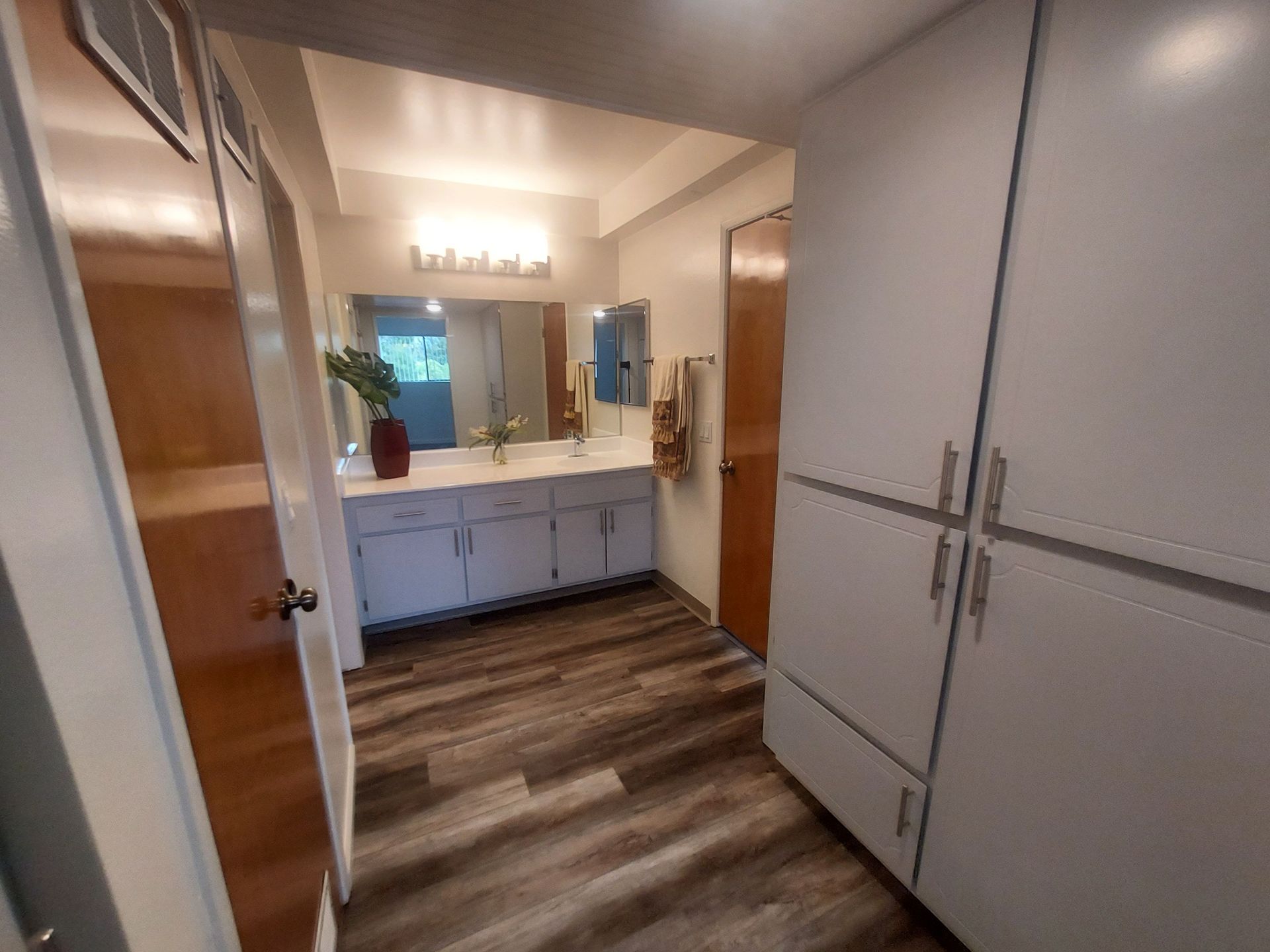 A hallway leading to a bathroom with a sink and a mirror.